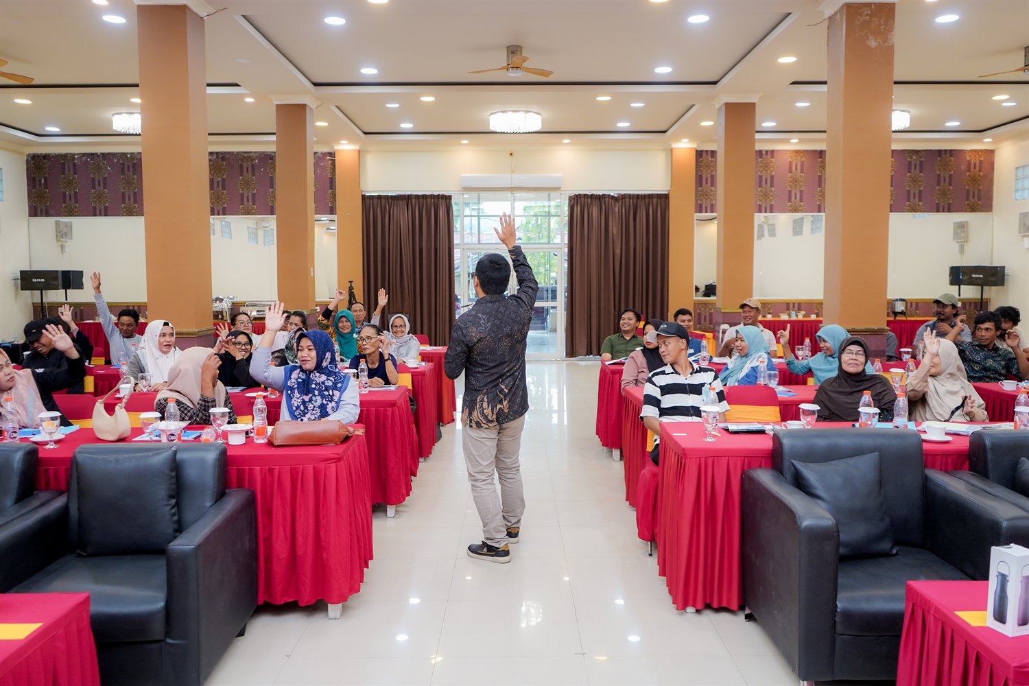 Suasana kelas pelatihan, peserta mengangkat tangan dan fasilitator di depan